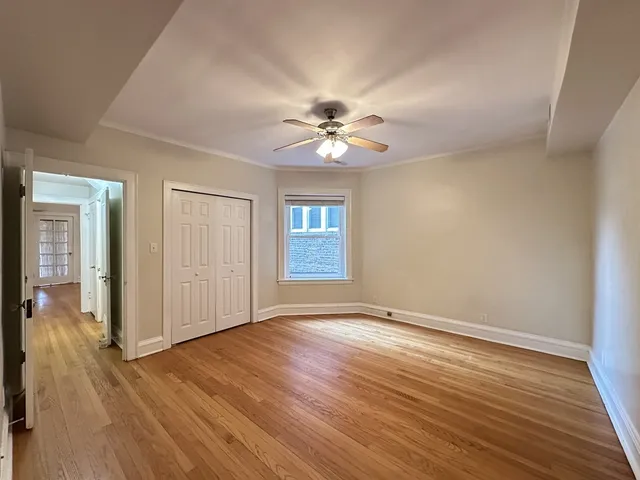 a view of an empty room with window and wooden floor
