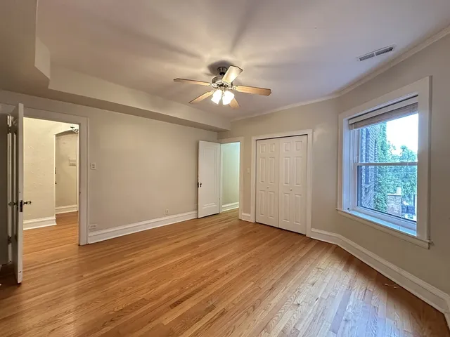 a view of an empty room with window and wooden floor