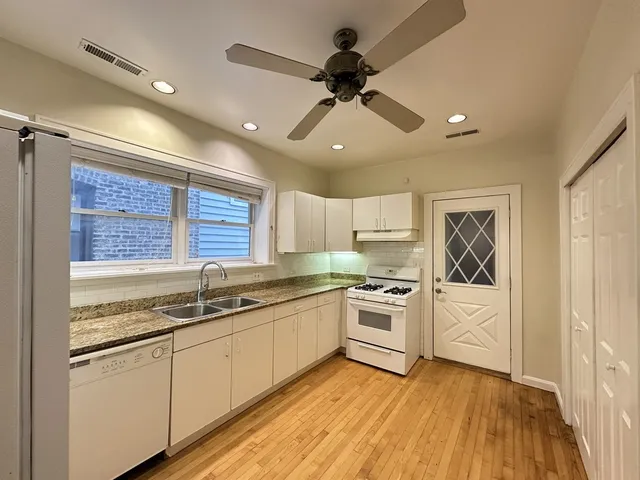 a kitchen with a stove a sink and white cabinets