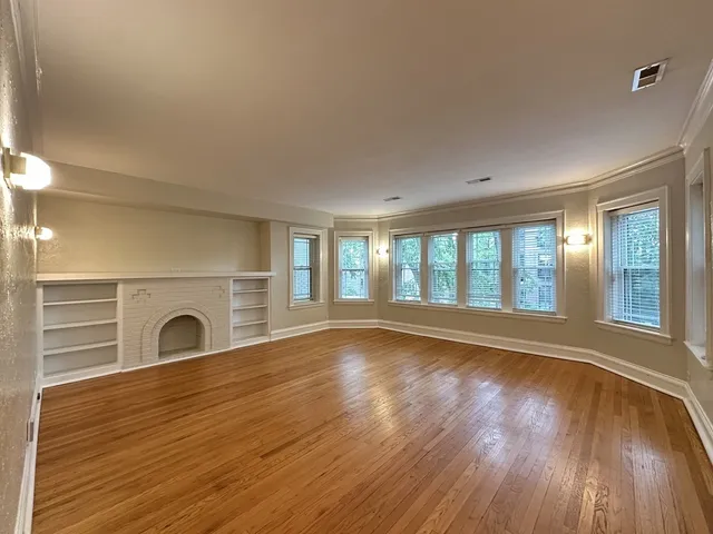 a view of an empty room with glass door and wooden floor