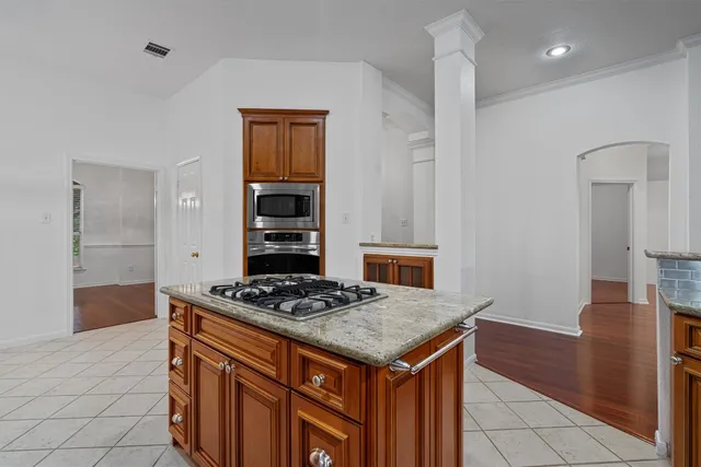 a kitchen that has a kitchen island wooden cabinets and stainless steel appliances