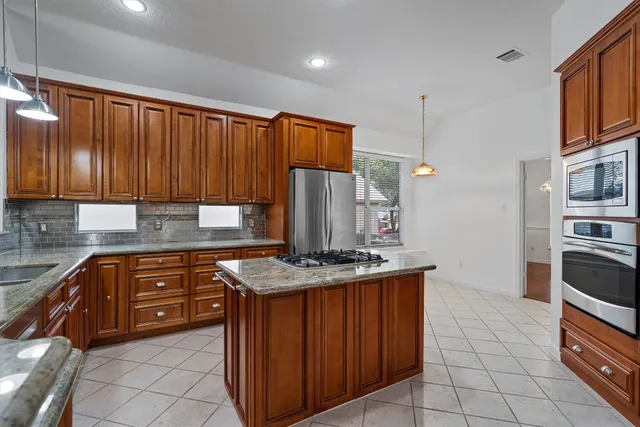 a kitchen with stainless steel appliances granite countertop a stove a sink and a refrigerator