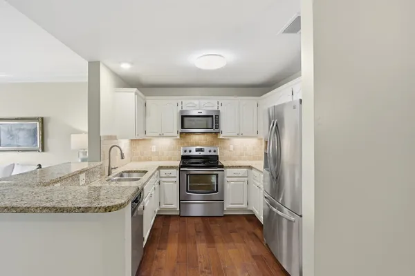 a kitchen with granite countertop stainless steel appliances a sink stove and refrigerator