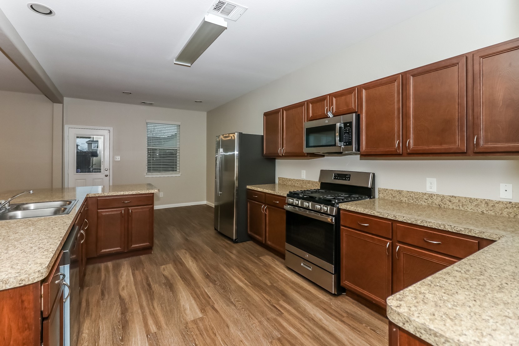 10311 Urban Oak Trail Houston, TX 77044 - Photo 6 of 15 a kitchen with stainless steel appliances granite countertop a stove top oven a sink dishwasher a dining table and chairs with wooden floor
