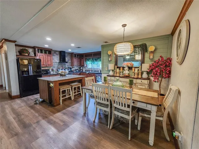 a kitchen with stainless steel appliances granite countertop a table chairs sink refrigerator and cabinets