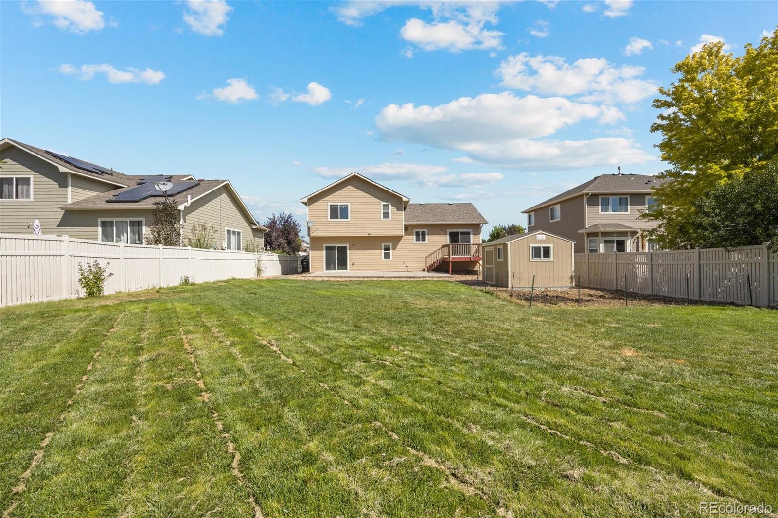 5328 Rustic Avenue Firestone, CO 80504 - Photo 18 of 22 a view of a white house next to a yard with big trees