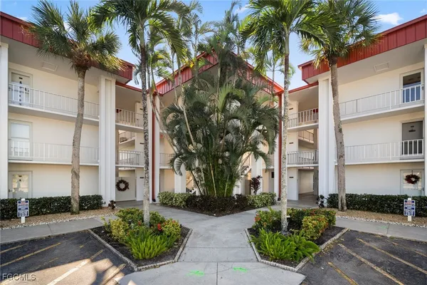 a front view of a multi story residential apartment building with yard and green space