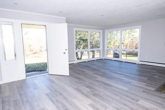 an empty room with wooden floor and windows