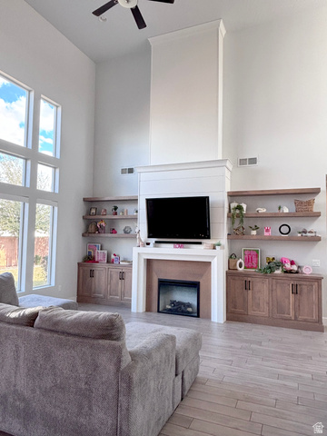 429 East Treasure Road Washington, UT 84780 - Photo 9 of 36 Living room featuring a high ceiling, a ceiling fan, light wood-style flooring, and a fireplace