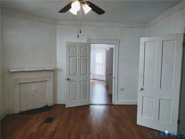 an empty room with wooden floor cabinet and windows