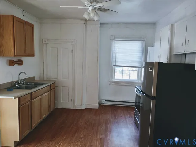 a kitchen with granite countertop a refrigerator stove and wooden floor