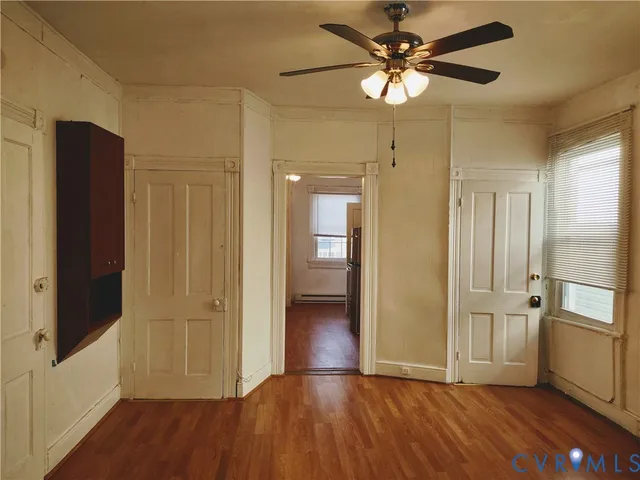 a view of empty room with wooden floor and fan