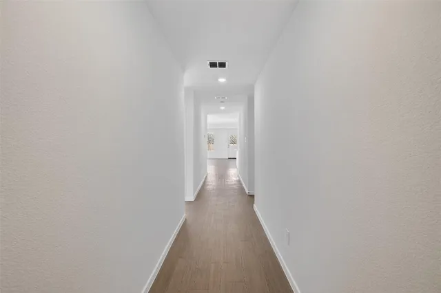 a view of a hallway with wooden floor and a bathroom