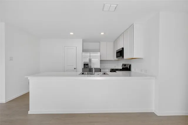 a view of kitchen with stainless steel appliances granite countertop white cabinets and refrigerator