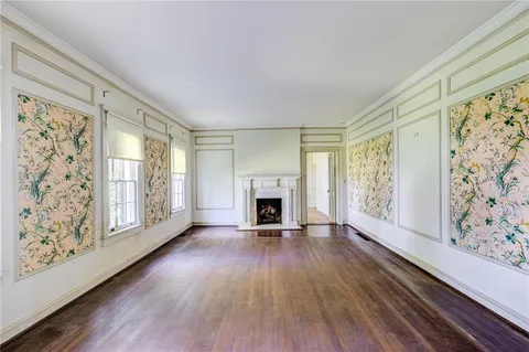 a view of a livingroom with wooden floor a fireplace and windows