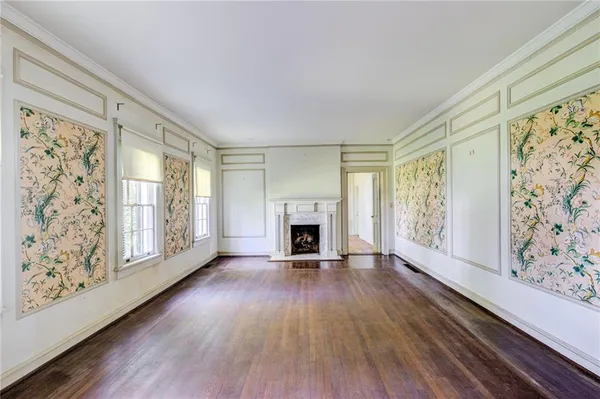 a view of a livingroom with wooden floor a fireplace and windows
