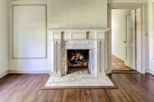 an empty room with wooden floor fireplace and staircase