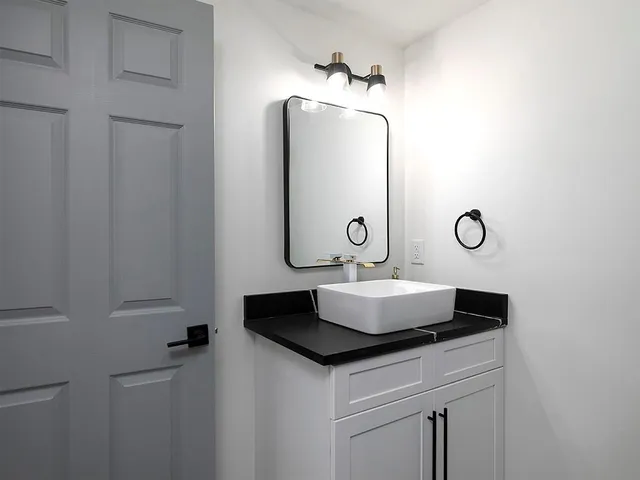 a bathroom with a granite countertop sink and a mirror