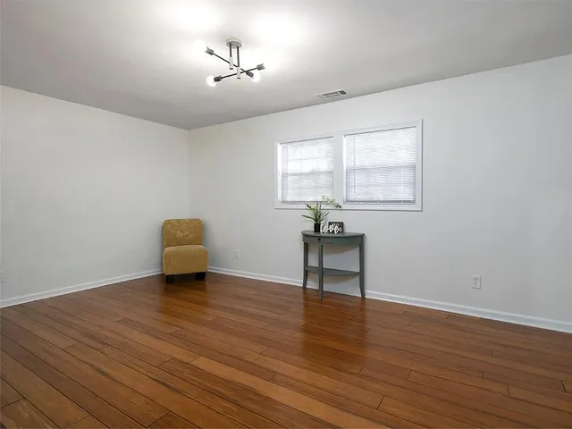 a view of an empty room with a window and wooden floor