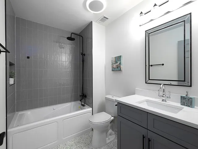 a bathroom with a bathtub shower sink vanity and toilet