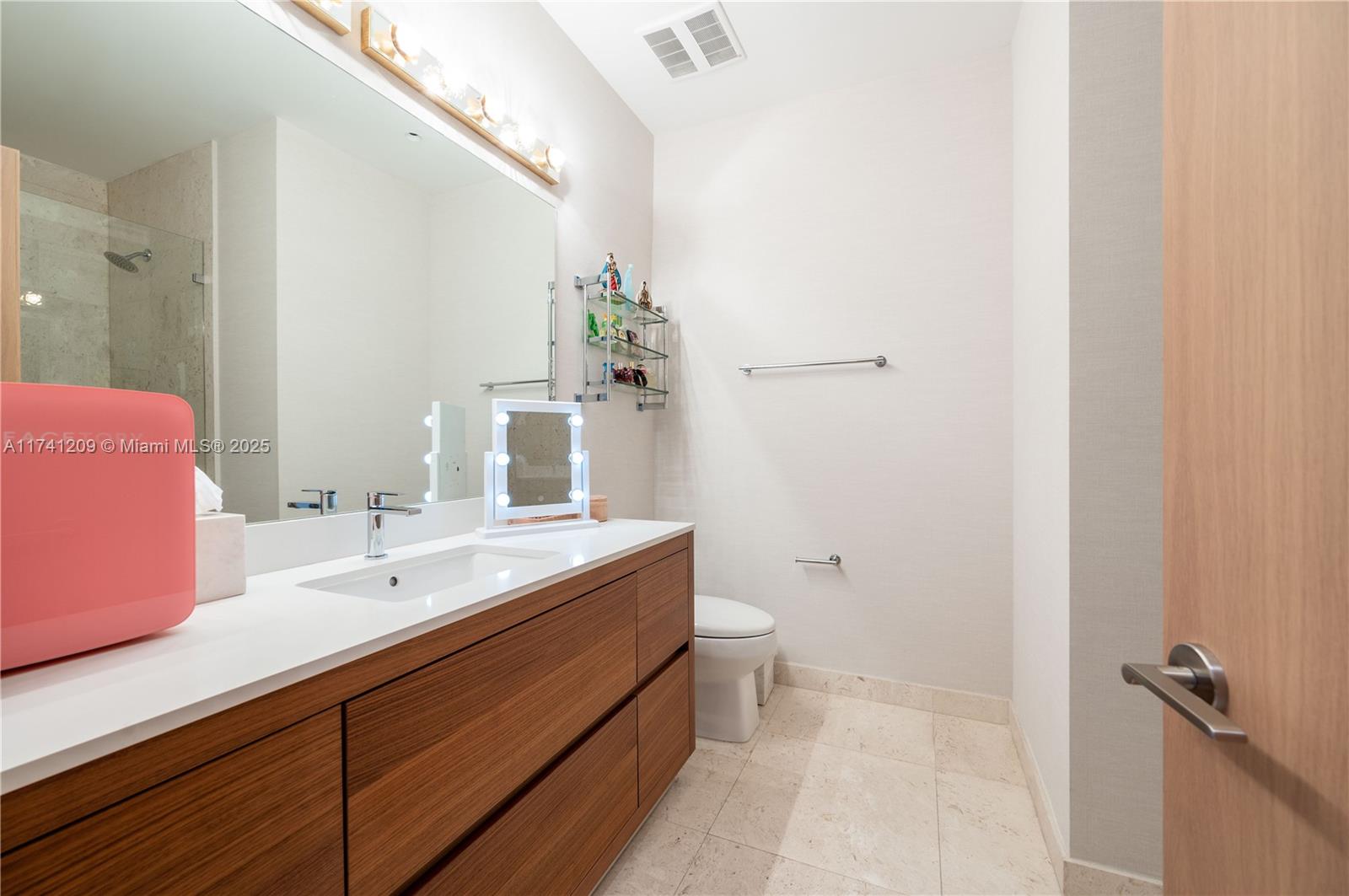 3581 East Glencoe Street, Unit 301 Miami, FL 33133 - Photo 16 of 21 a bathroom with a sink a toilet and a mirror