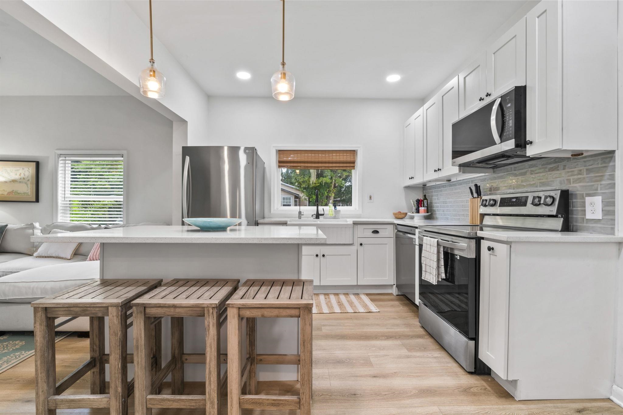 635 Madeore Street St. Augustine, FL 32084 - Photo 13 of 44 a kitchen with stainless steel appliances granite countertop a stove top oven a sink dishwasher a dining table and chairs with wooden floor