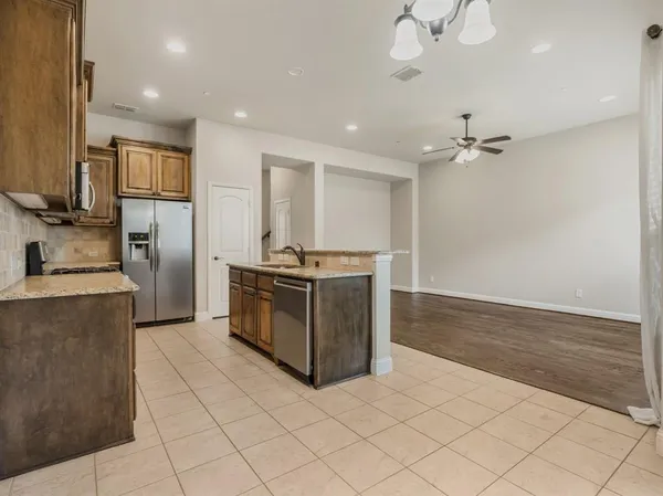 a kitchen with stainless steel appliances granite countertop a stove top oven a sink dishwasher and a refrigerator with wooden floor