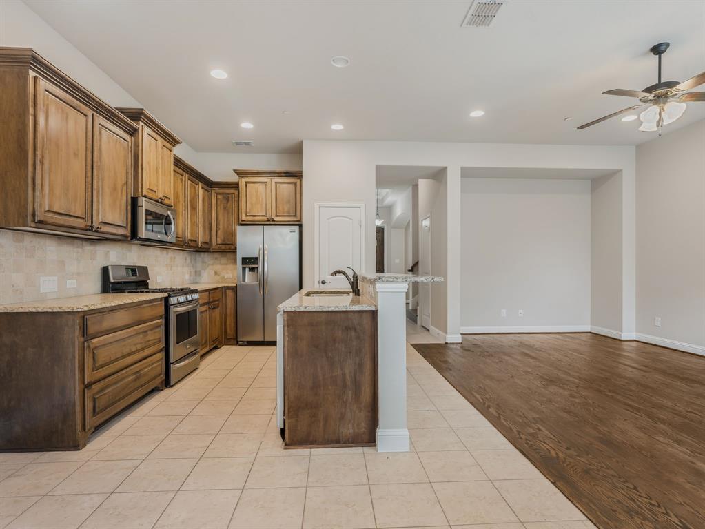 4672 Cecile Road Plano, TX 75024 - Photo 17 of 31 a kitchen with stainless steel appliances granite countertop a stove top oven a sink dishwasher and a refrigerator with wooden floor