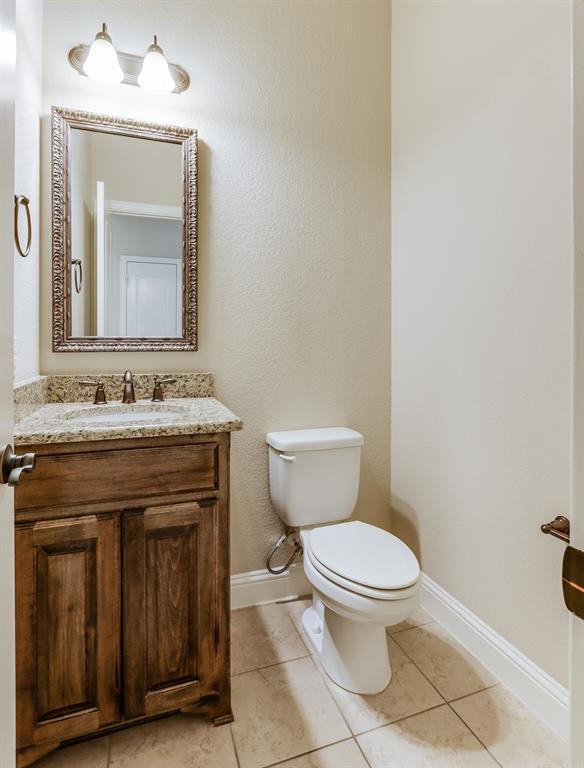 4672 Cecile Road Plano, TX 75024 - Photo 19 of 31 a bathroom with a granite countertop toilet a sink and a mirror