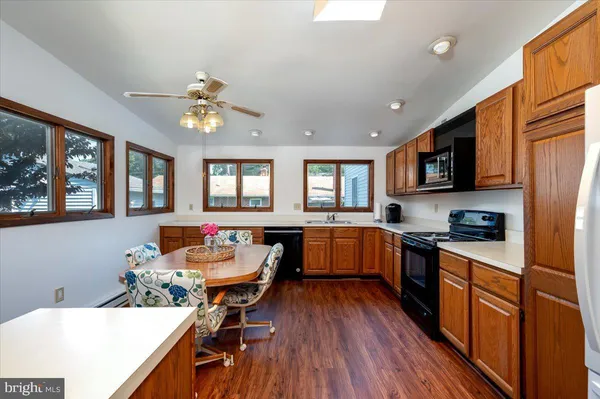 a kitchen with stainless steel appliances granite countertop hardwood floor sink stove dining table and chairs