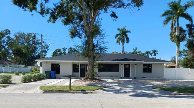 a view of a house with a yard and palm trees