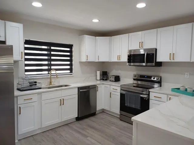 a kitchen with stainless steel appliances granite countertop a stove a sink and a microwave