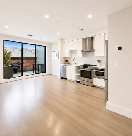 a large kitchen with stainless steel appliances granite countertop a stove and a large window