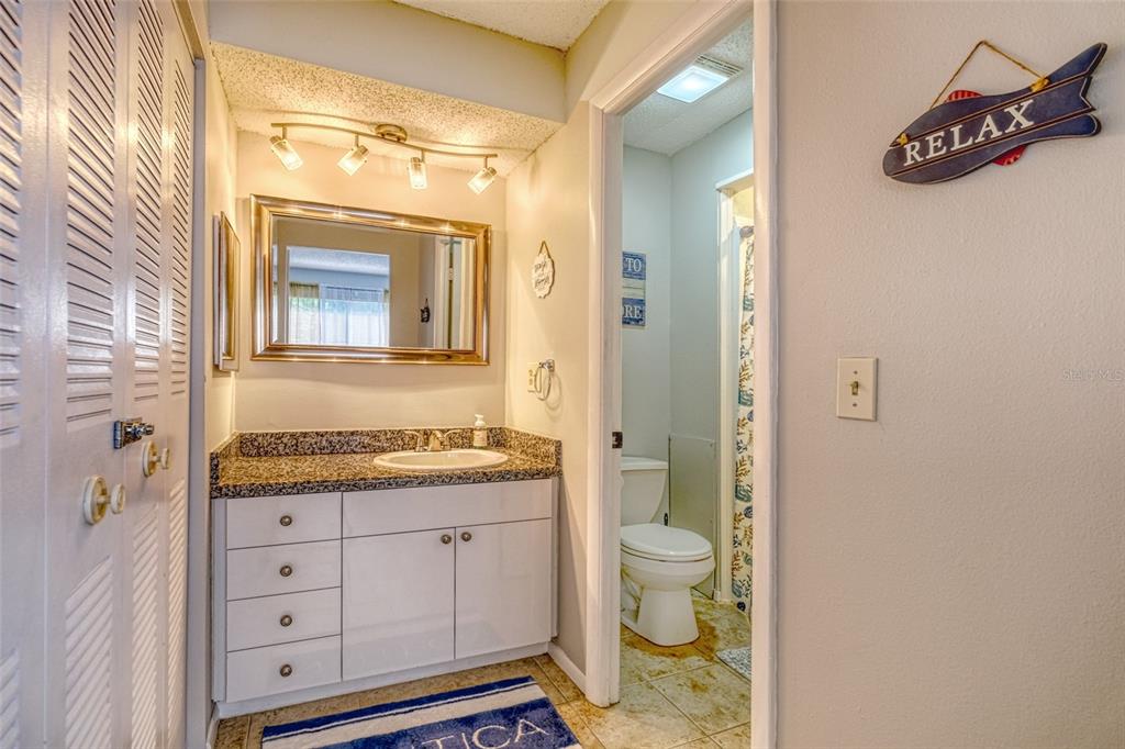 13714 Mission Oaks Boulevard, Unit 13714 Seminole, FL 33776 - Photo 14 of 24 a bathroom with a granite countertop sink toilet and mirror