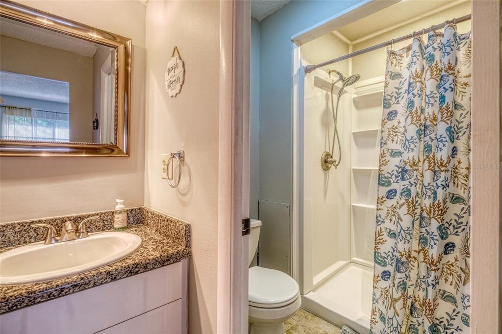 13714 Mission Oaks Boulevard, Unit 13714 Seminole, FL 33776 - Photo 15 of 24 a bathroom with a granite countertop sink toilet and shower