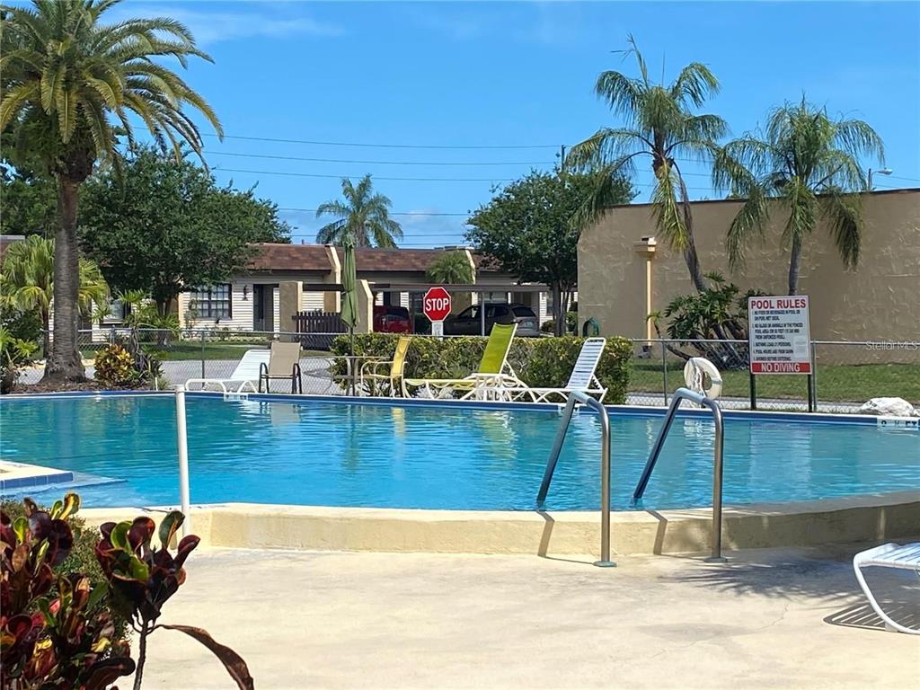 13714 Mission Oaks Boulevard, Unit 13714 Seminole, FL 33776 - Photo 23 of 24 a view of a swimming pool with a patio and a garden