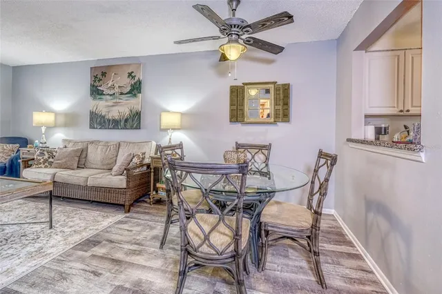 a view of a livingroom and a dining room with wooden floor and a chandelier fan