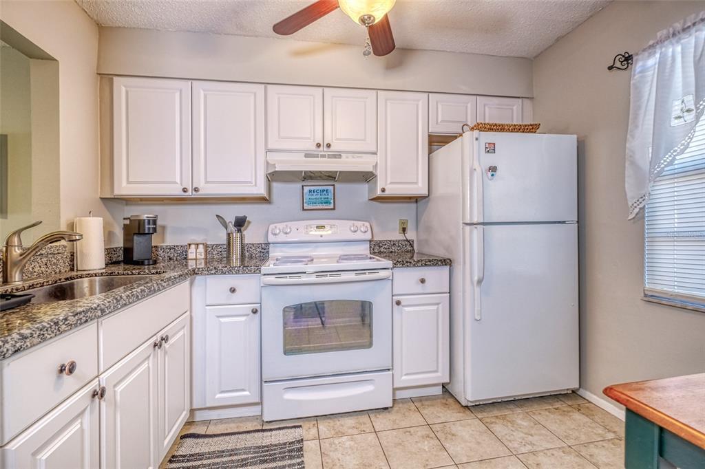 13714 Mission Oaks Boulevard, Unit 13714 Seminole, FL 33776 - Photo 10 of 24 a kitchen with a white cabinets and white appliances