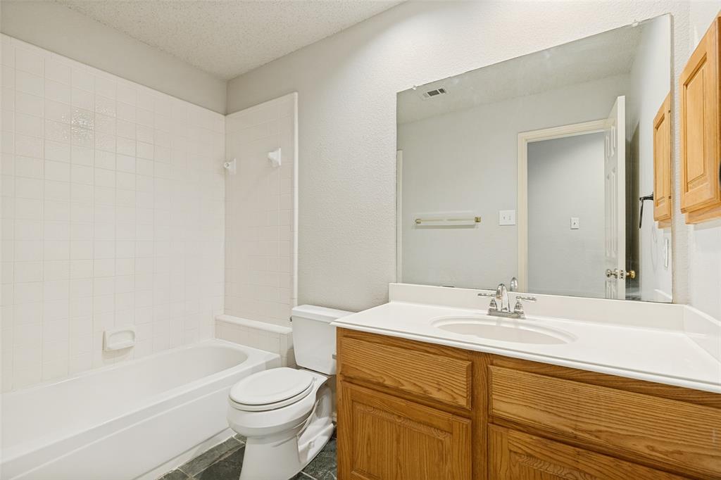 1215 Spring Creek Drive Allen, TX 75002 - Photo 23 of 40 Bathroom featuring a tub/shower combination with white subway tile surround, a single vanity with a white countertop, and wood-finish cabinetry