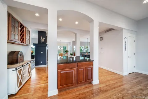 a kitchen with stainless steel appliances granite countertop a stove a refrigerator a kitchen island a dining table and chairs with wooden floor