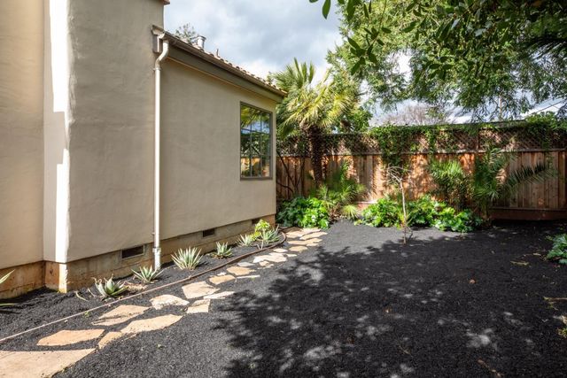 a backyard of a house with plants and trees beside it