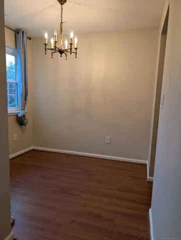 an empty room with wooden floor and chandelier