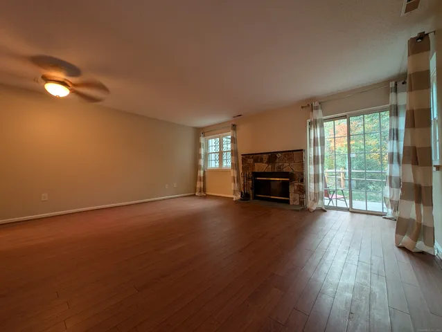 an empty room with fireplace wooden floor and windows
