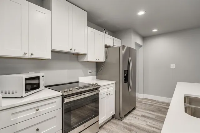 a kitchen with stainless steel appliances white cabinets and a stove a refrigerator with wooden floor