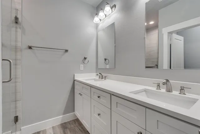 a bathroom with a double vanity sink a large mirror and shower