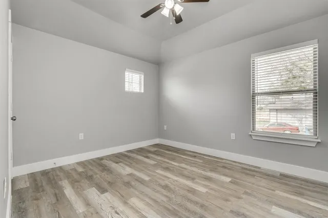 a view of empty room with wooden floor and fan