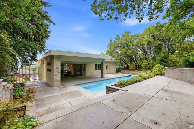 1389 Millbrook Way Bountiful, UT 84010 - Photo 66 of 74 Outdoor concrete patio featuring a rectangular swimming pool, an adjacent covered patio area, and integrated planters