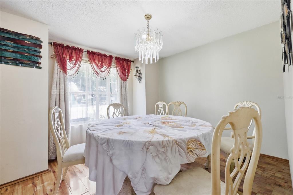3027 Queens Gate Road Orlando, FL 32818 - Photo 20 of 34 a dining room with furniture a chandelier and window