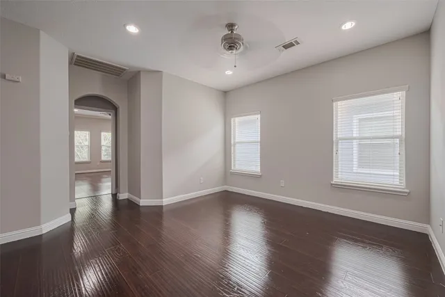 an empty room with wooden floor and windows