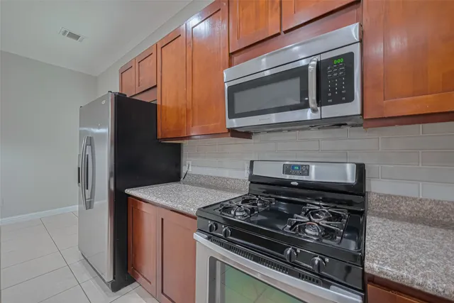 a kitchen with stainless steel appliances granite countertop white cabinets and black stove top oven